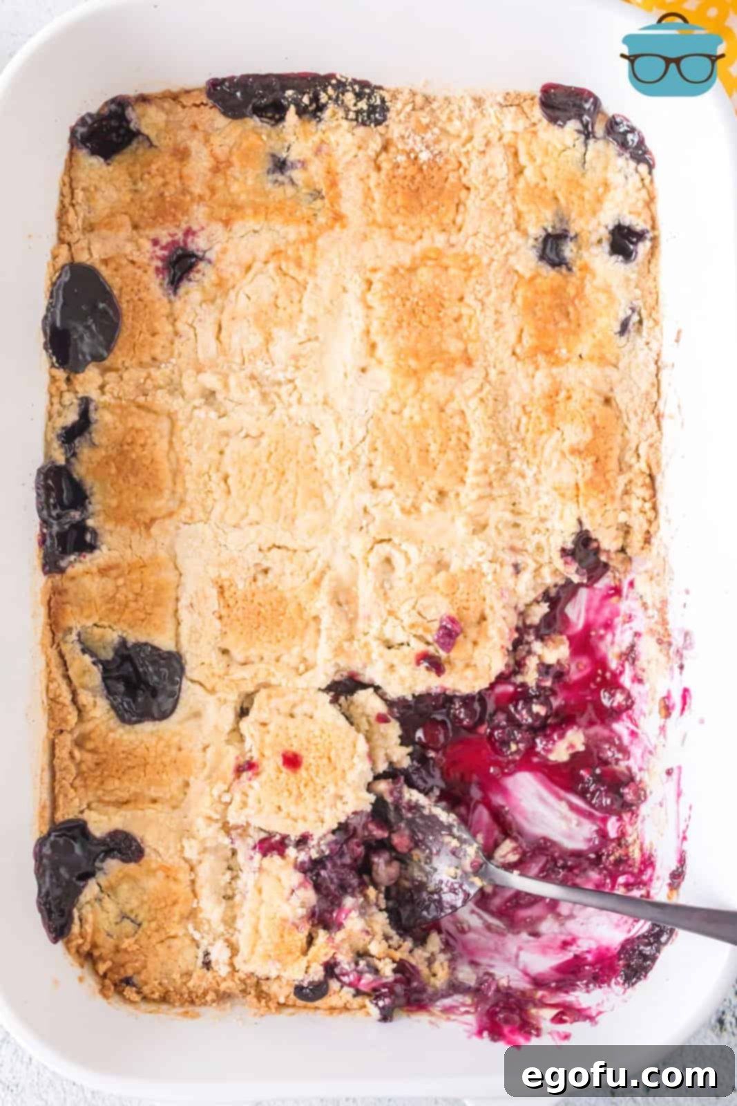 A baking dish with Blueberry Dump Cake in it and a serving taken out.