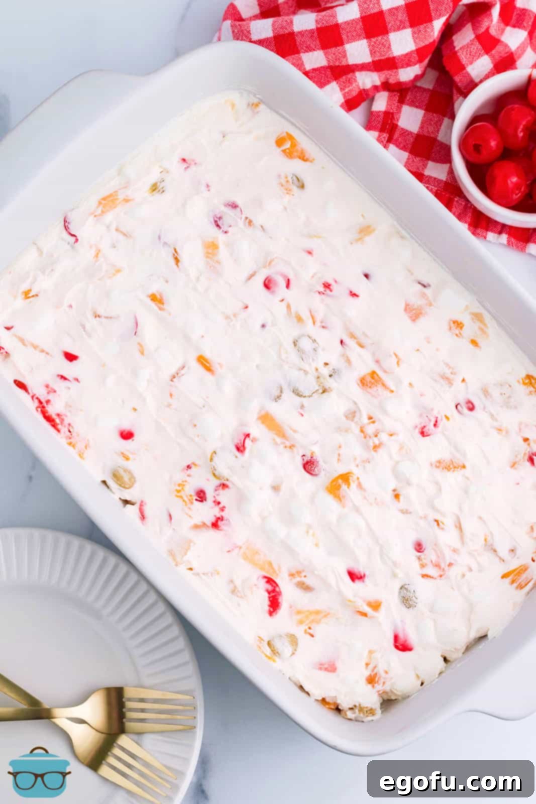 A baking dish filled with the prepared frozen fruit salad mixture, covered with plastic wrap and ready for freezing.