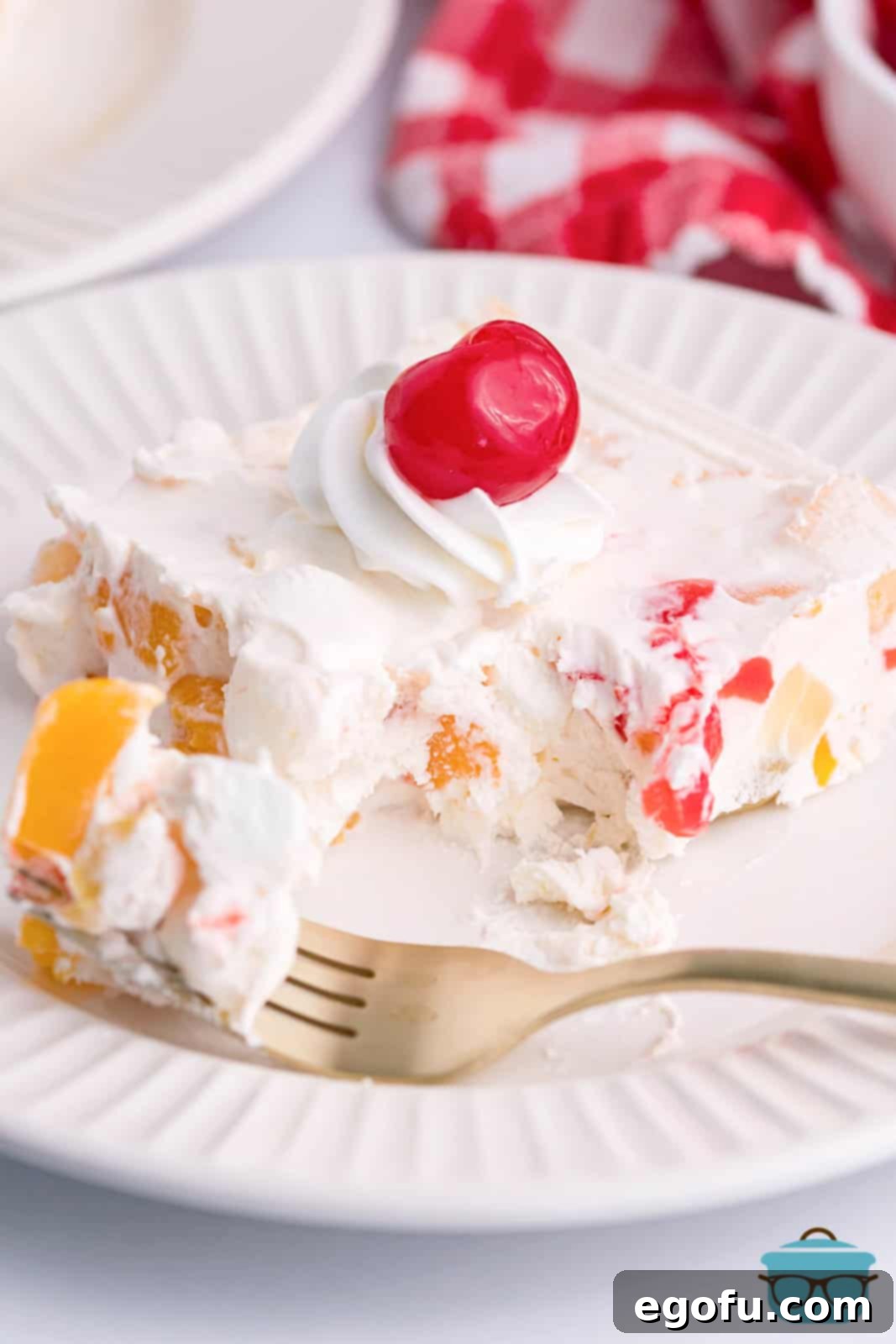 A beautiful serving of frozen fruit salad on a plate with a fork, showing the creamy, colorful dessert ready to be enjoyed.