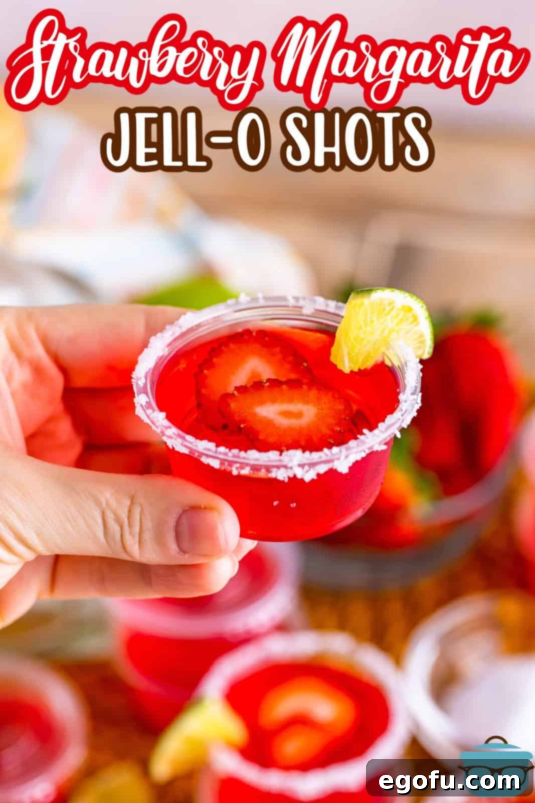 A hand holding a Strawberry Margarita Jello Shots.