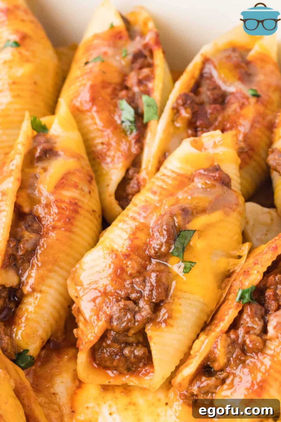 Close up looking at a few taco stuffed shells, generously garnished with fresh cilantro and a dollop of sour cream.