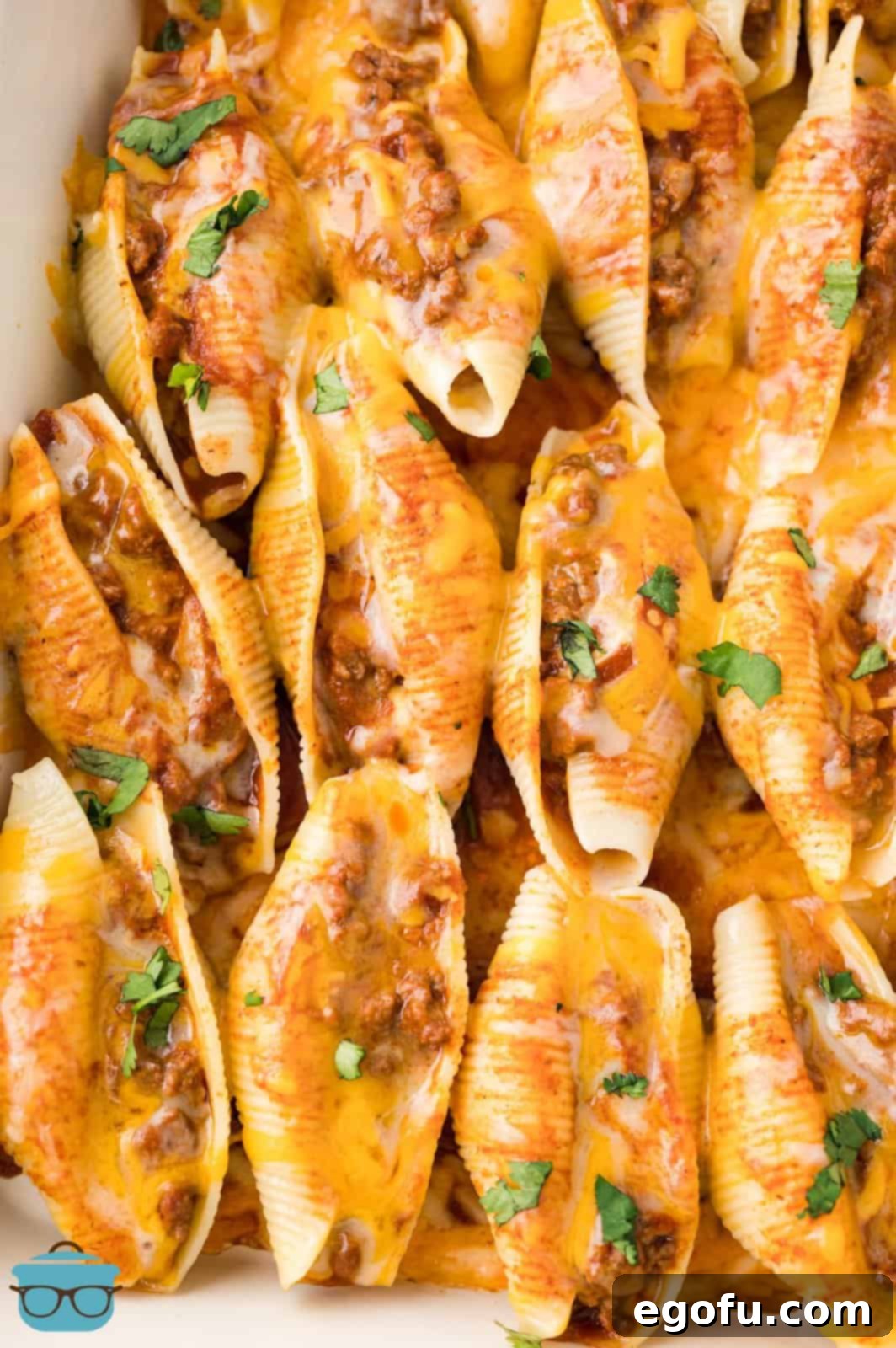 A baking dish full of freshly baked Taco Stuffed Shells, glistening with melted, bubbly cheese, just removed from the oven.