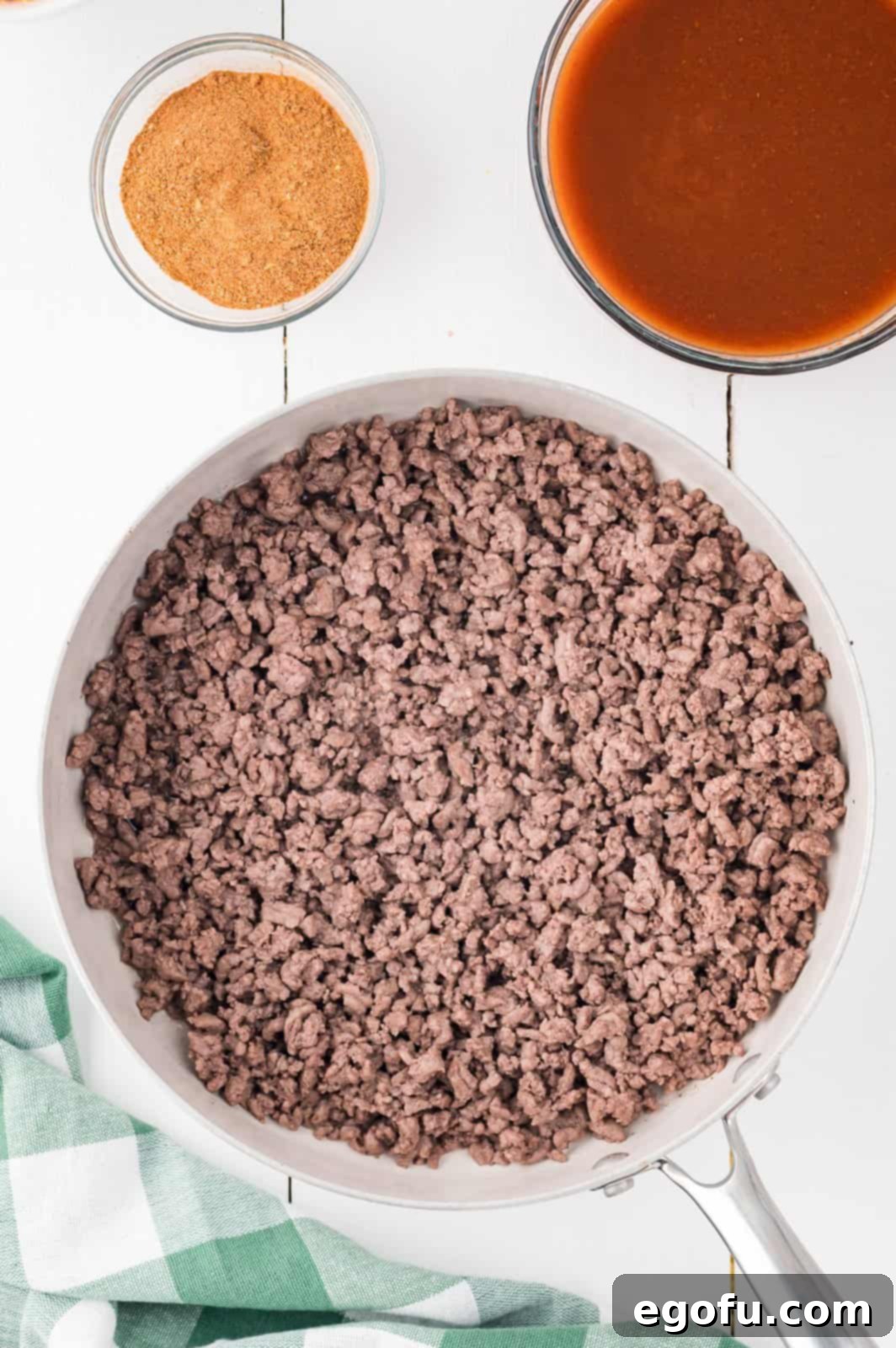 A large skillet containing perfectly cooked and crumbled ground beef, ready for the next step of flavoring.