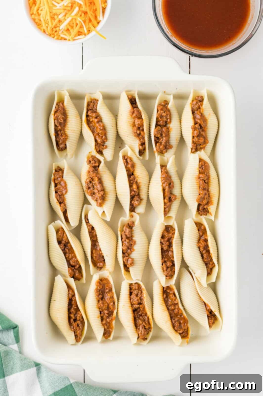 Taco stuffed shells meticulously arranged in rows within a baking dish, waiting for the final sauce and cheese.