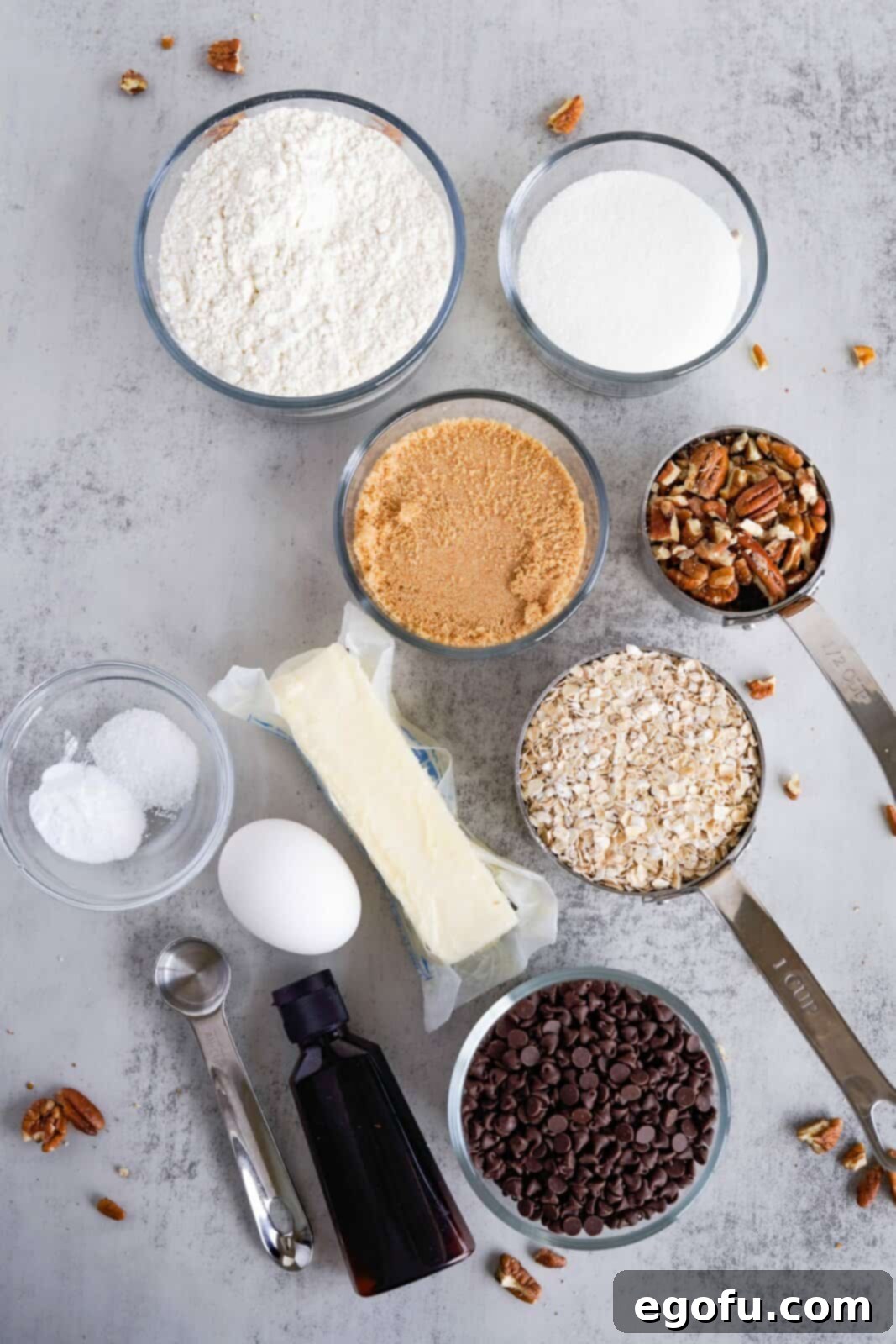 Oatmeal Chocolate Chip Delights 4 Ingredients laid out for Oatmeal Chocolate Chip Cookies: butter, sugars, eggs, vanilla, flour, baking soda, salt, quick oats, mini chocolate chips, and pecans, all ready to be combined.