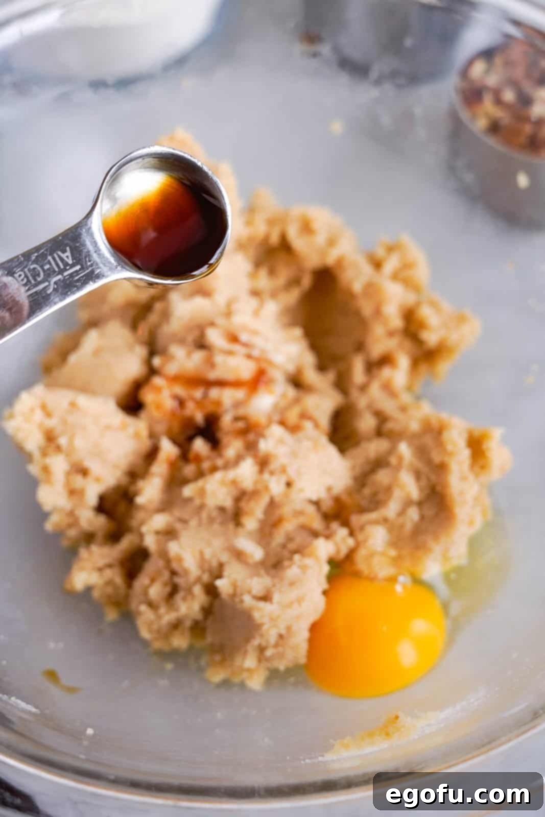 Oatmeal Chocolate Chip Delights 6 Adding egg and vanilla extract to creamed butter and sugar mixture for cookie dough, mixing until fully combined.