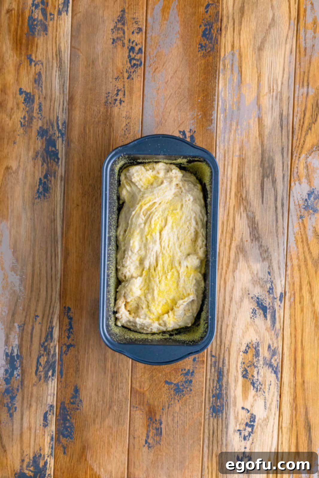 bread dough sprinkled with cornmeal in a loaf pan. 