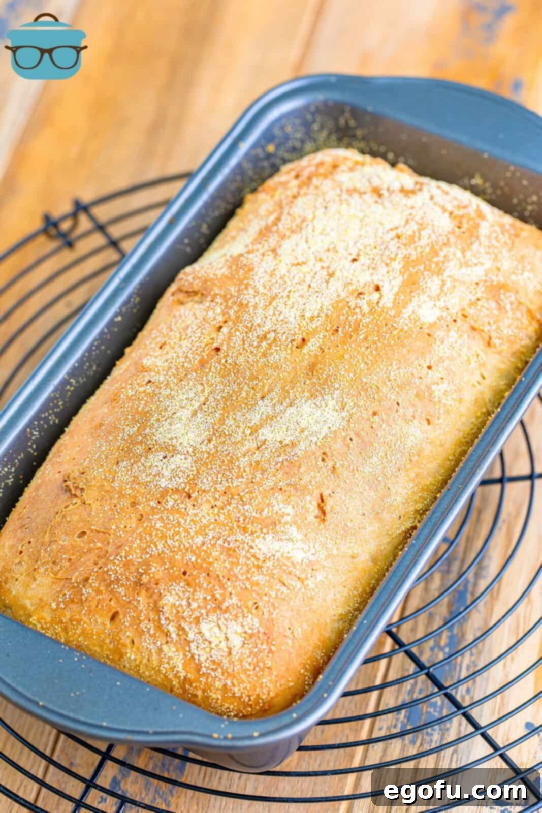 fully baked English muffin bread in a metal pan sitting on a wiring rack to cool.