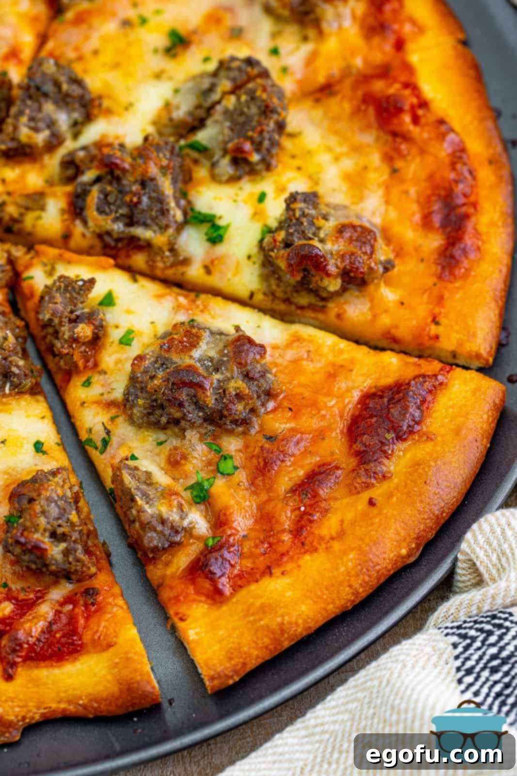 Close up looking at a slice of meatball pizza, showcasing the crispy crust, tender meatballs, and melted cheese.