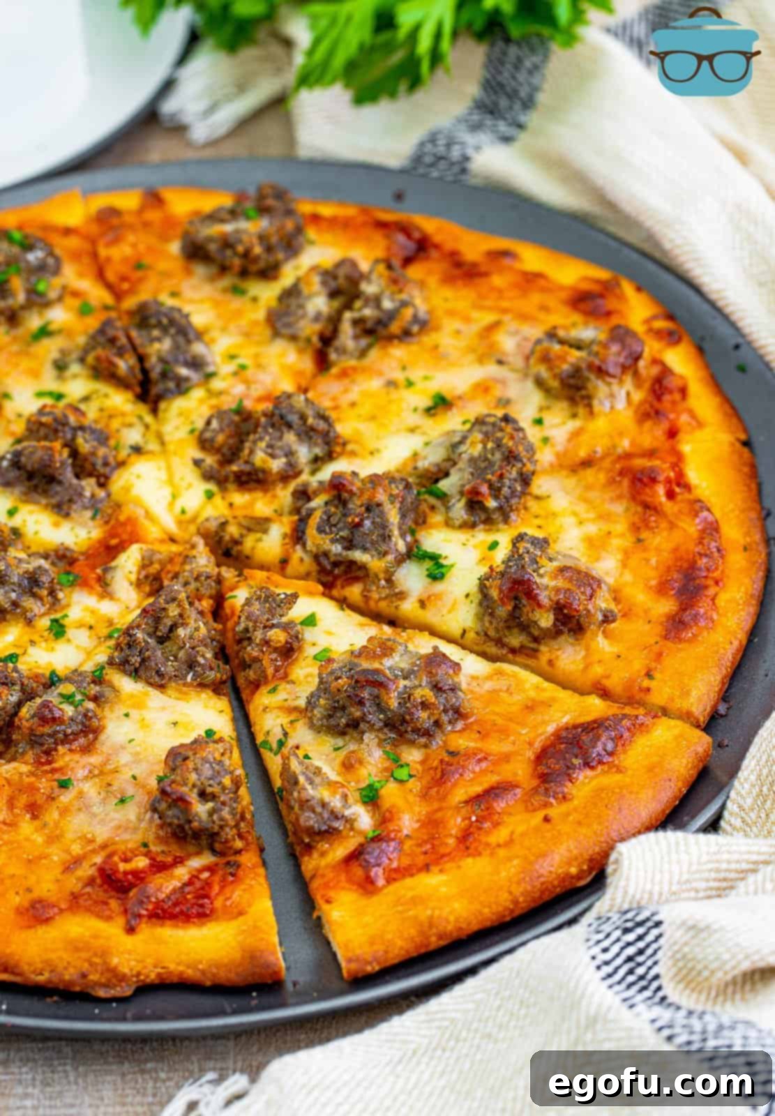 A beautifully baked and garnished meatball pizza, sliced and ready for serving in a rustic dish.
