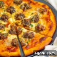 A piece of meatball pizza being removed from the rest of the pizza, highlighting the delectable layers.