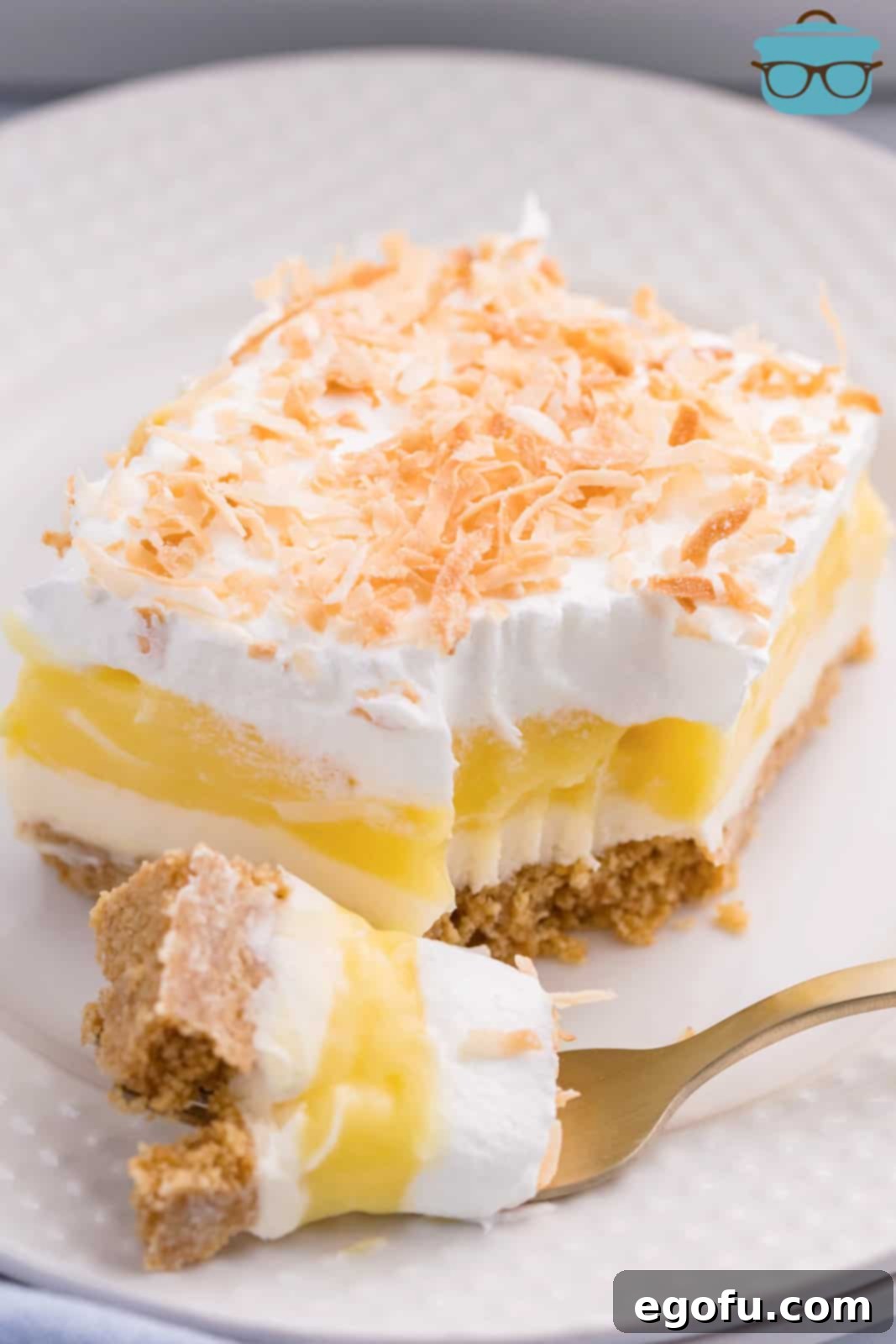 A slice of Coconut Cream Lush dessert with a bite taken out, showing its creamy layers.