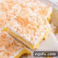 A beautifully presented slice of Coconut Cream Lush dessert, showing all its distinct layers.