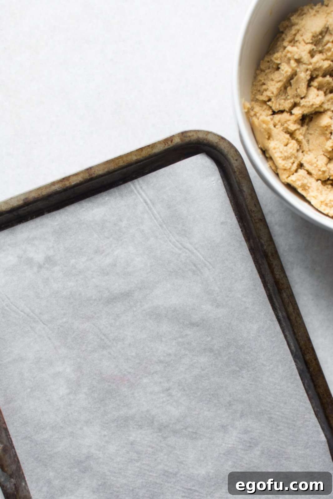 Top view of a baking sheet perfectly lined with parchment paper, ready for food preparation.