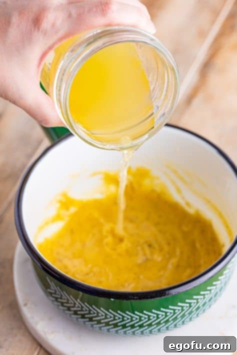 Chicken broth being poured in a dutch oven.