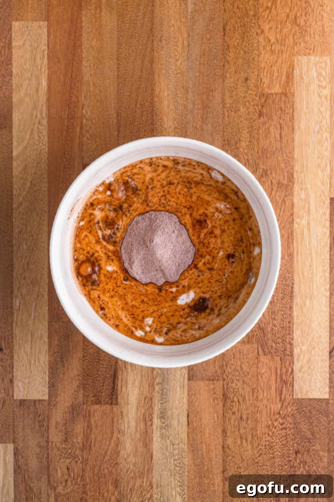 Golden Butterfinger Dream 10 A mixing bowl with chocolate pudding mix being whisked with cold milk, showing the pudding starting to thicken.