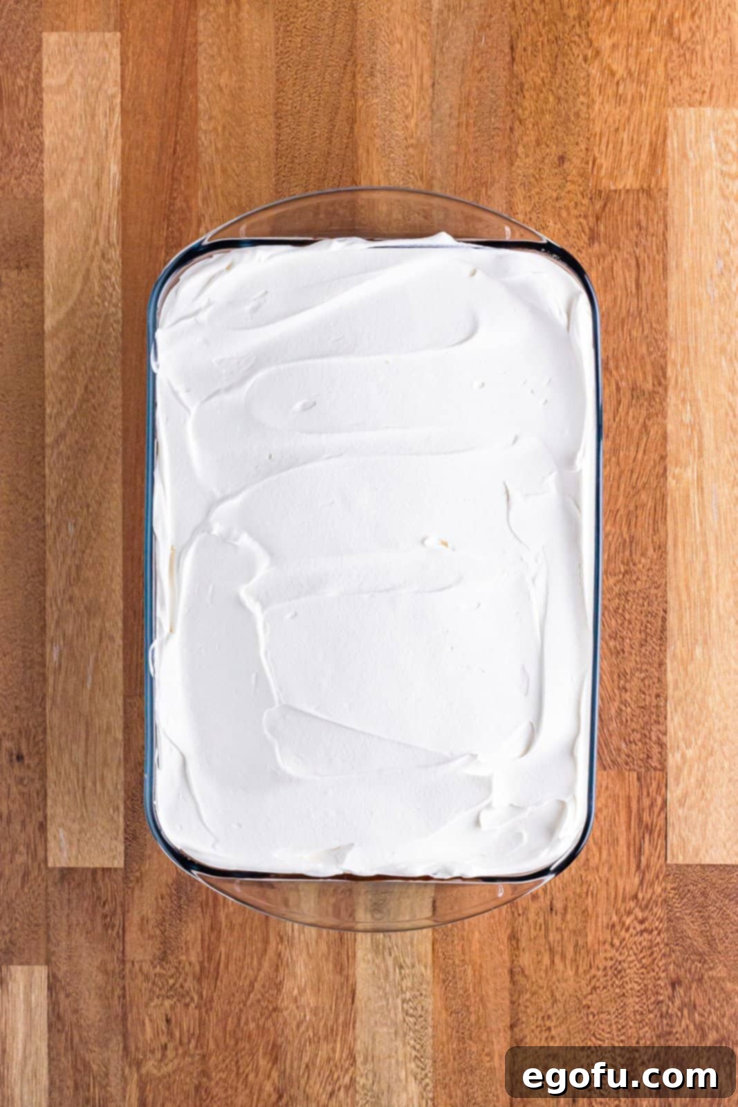 Golden Butterfinger Dream 12 The final layer of fluffy Cool Whip evenly spread over the chocolate pudding, completing the layered Butterfinger Lush dessert.