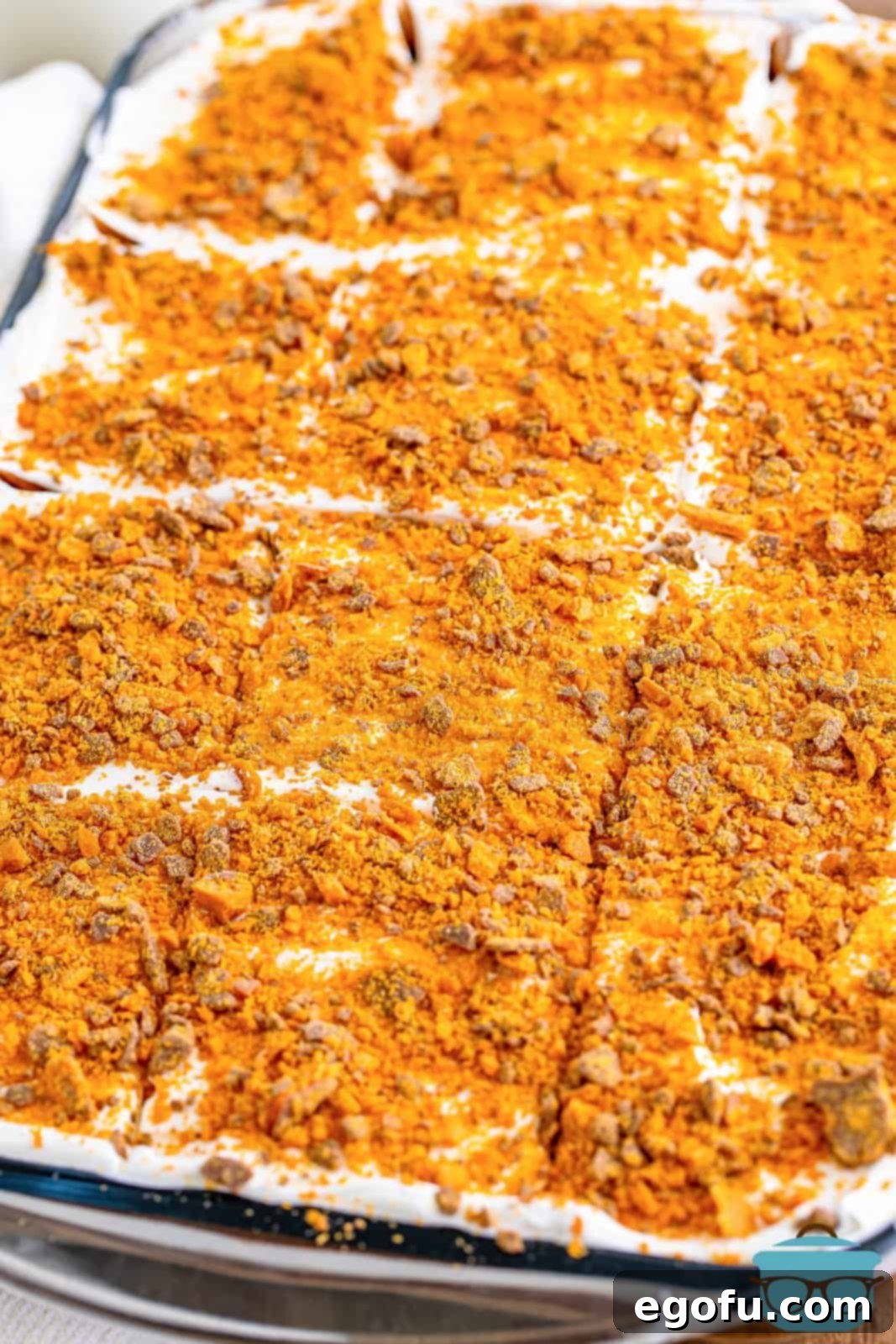 Golden Butterfinger Dream 13 A top-down view of the finished Butterfinger Lush in a baking dish, generously garnished with crushed Butterfinger candy pieces.