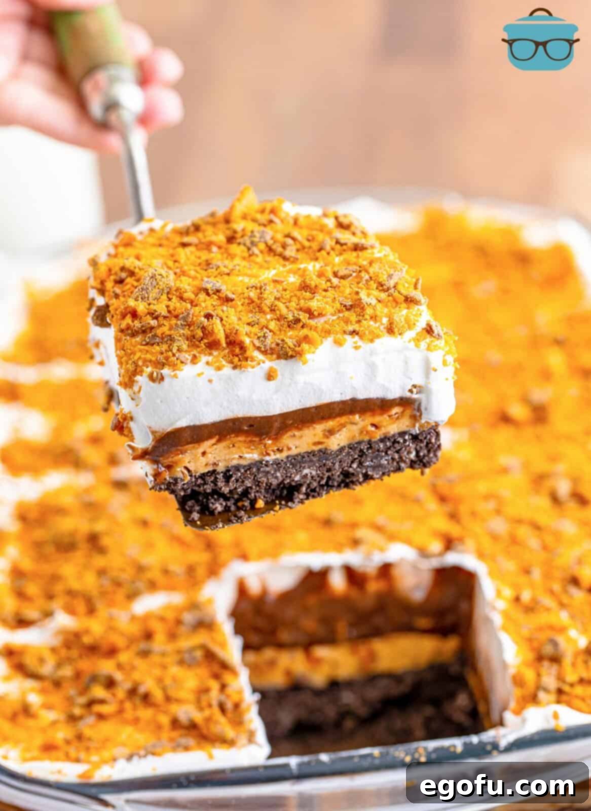 Golden Butterfinger Dream 14 A serving utensil holding a perfect slice of Butterfinger Lush dessert, showcasing all the distinct layers.