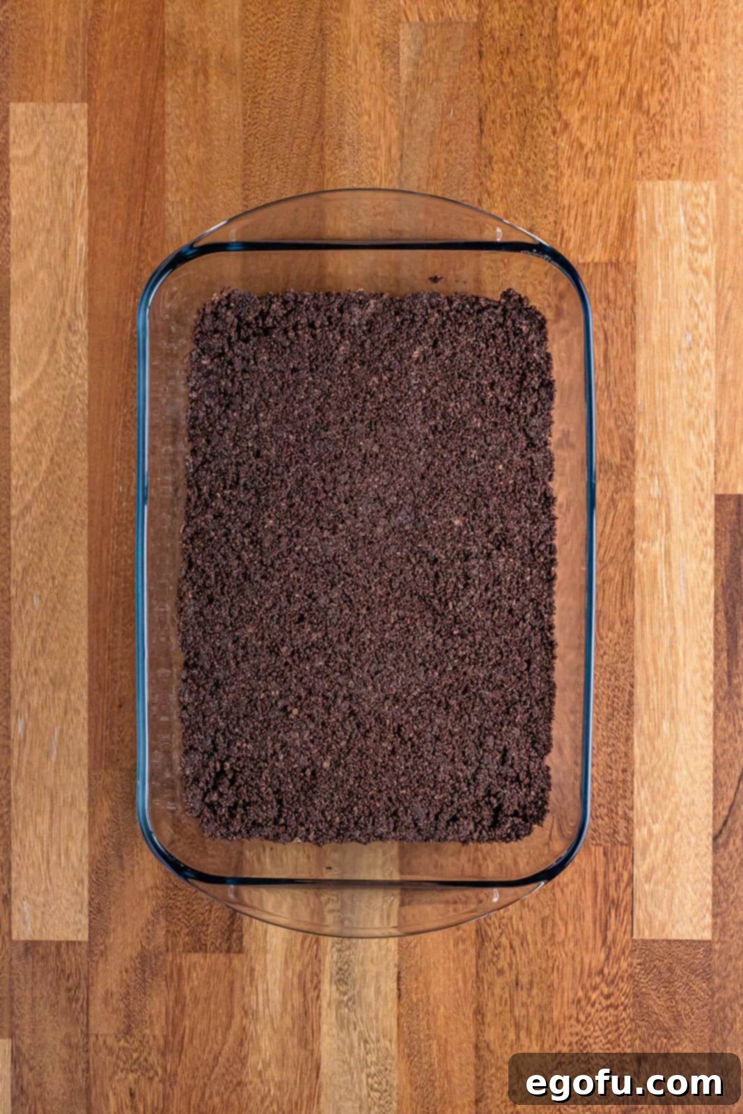 Golden Butterfinger Dream 6 A 9x13 inch baking dish with a perfectly pressed Oreo cookie crust, chilling in the refrigerator.