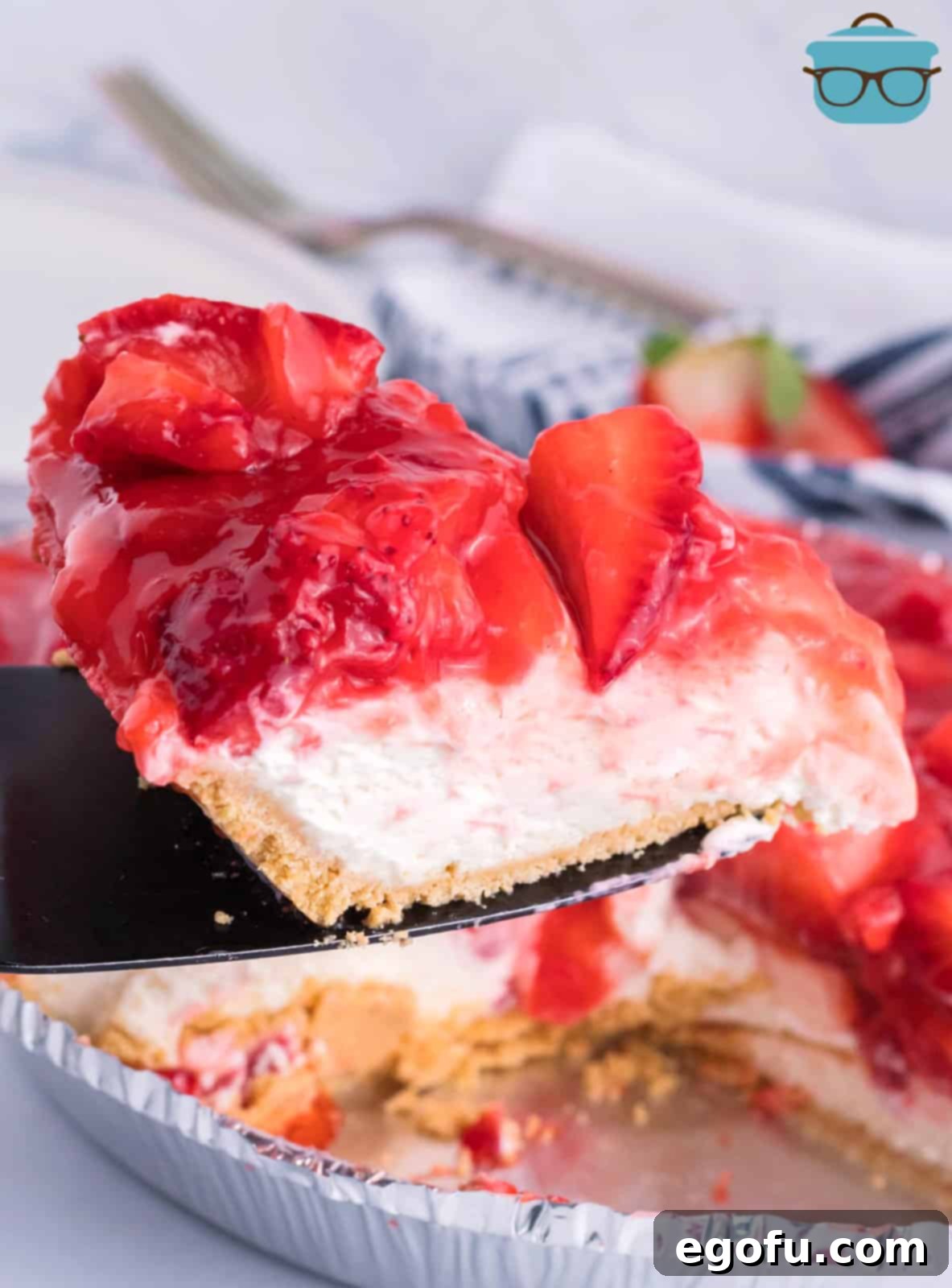 A pie serving utensil with a slice of No-Bake Strawberry Cream Cheese Pie, showcasing its layers.