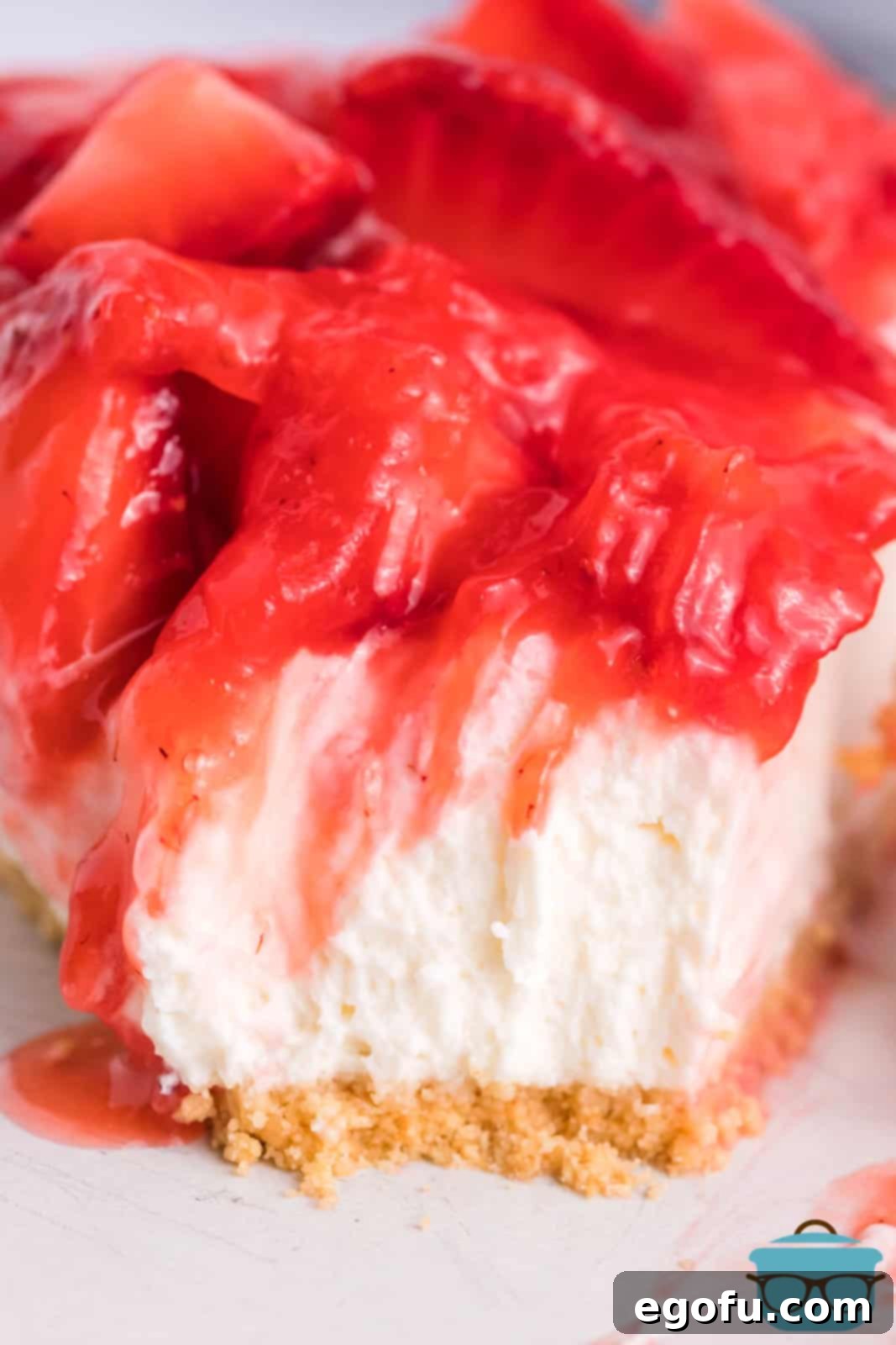 A close-up of a slice of Strawberry Cream Cheese Pie with a bite taken out, emphasizing its texture.