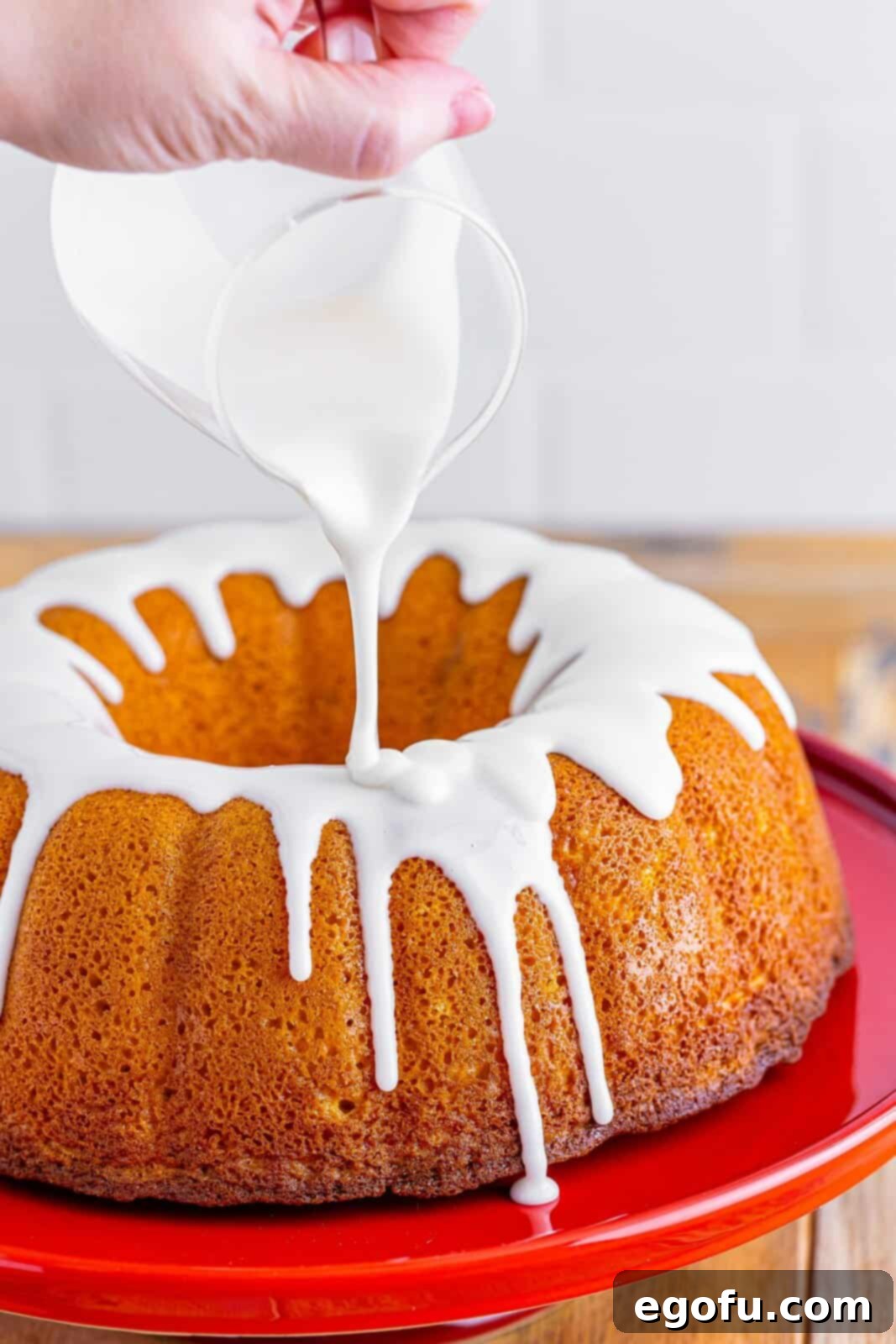 The powdered sugar glaze being poured on a Sock It To Me Cake. 