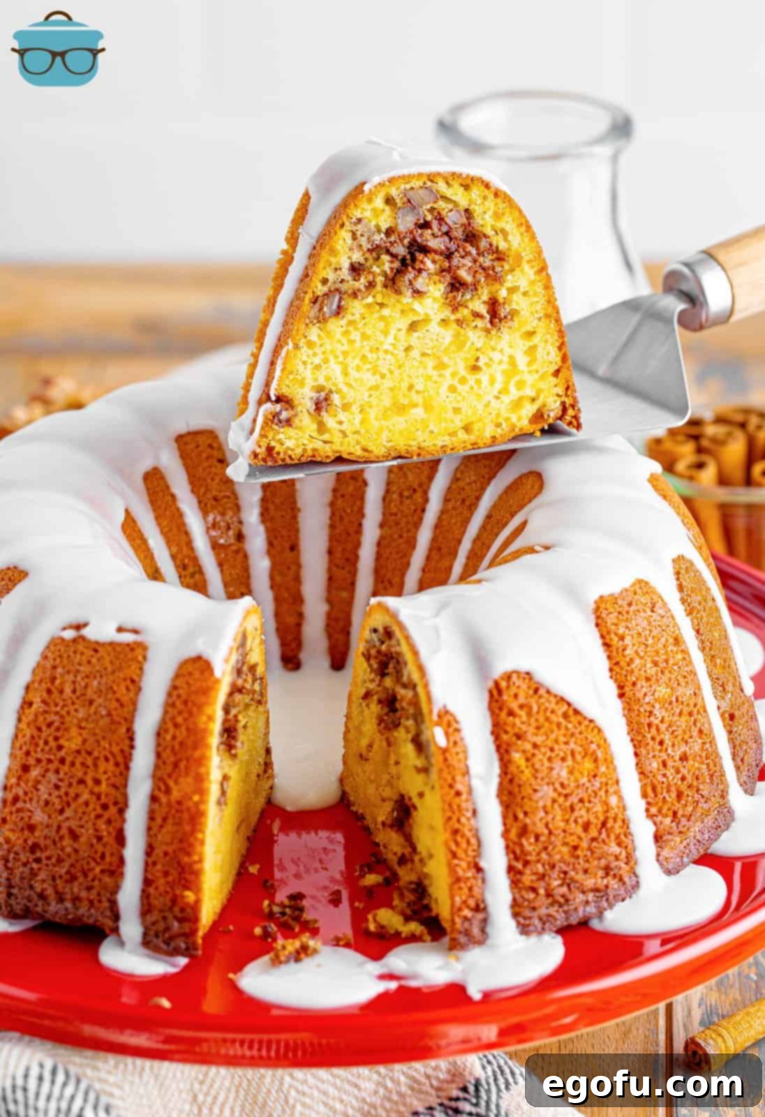 A Sock it to me Cake with a slice being held over it with a serving utensil.