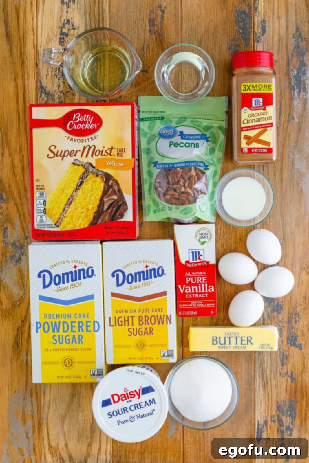 Yellow cake mix, granulated sugar, brown sugar, eggs, vegetable oil, water, sour cream, chopped pecans, ground cinnamon, salted butter, powdered sugar, milk, and vanilla extract. 