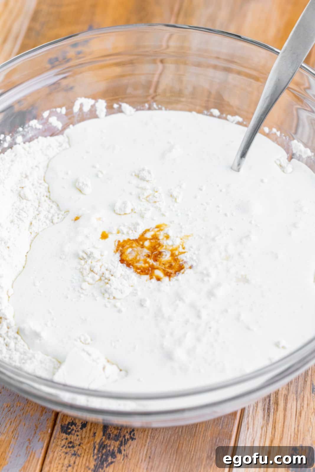 Sun-Kissed Peach Butter Swim Biscuits 6 The mixing bowl now contains the dry ingredients, heavy cream, and vanilla extract, being stirred into a sticky dough.