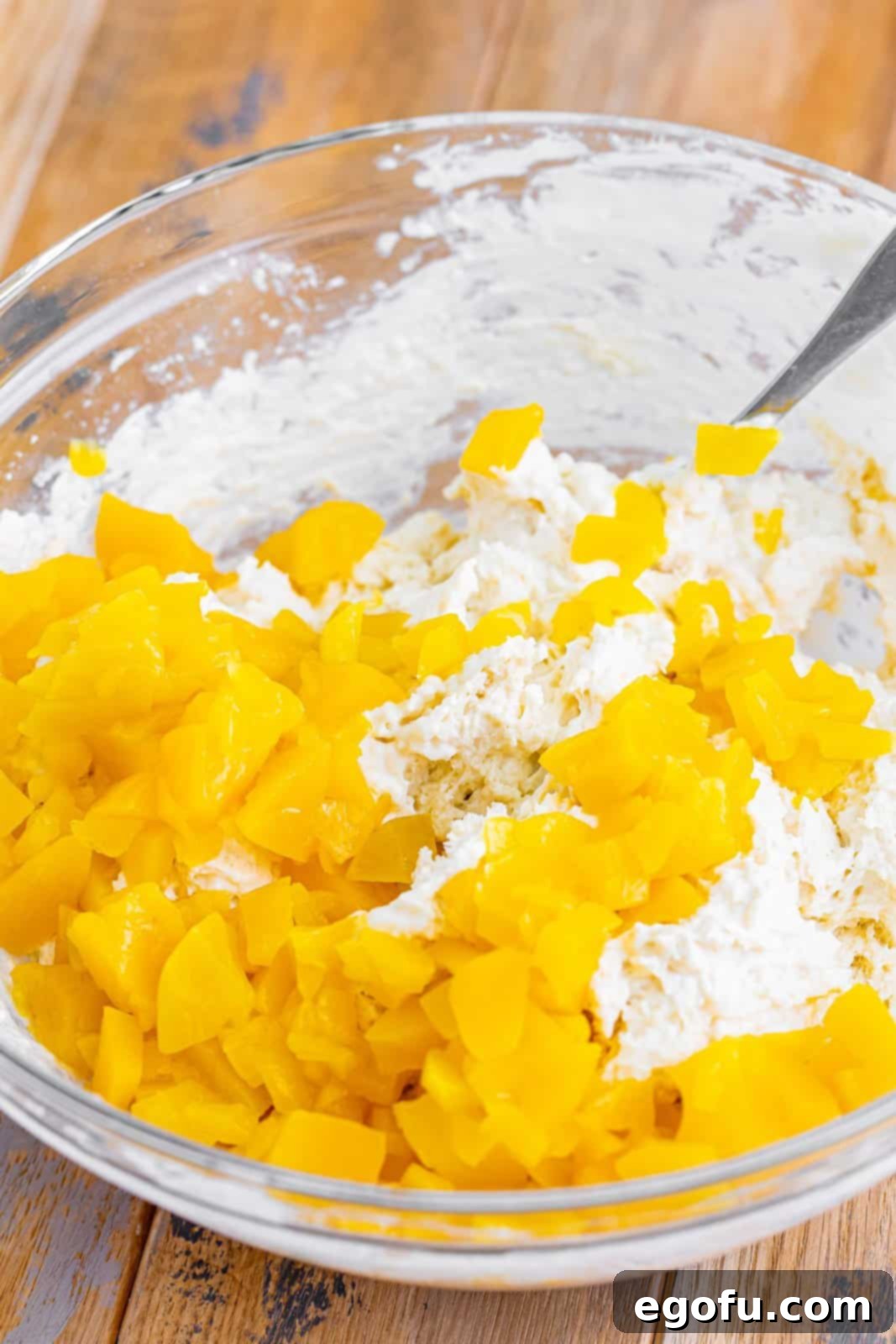 Sun-Kissed Peach Butter Swim Biscuits 7 Diced canned peaches gently folded into the biscuit dough in a mixing bowl.