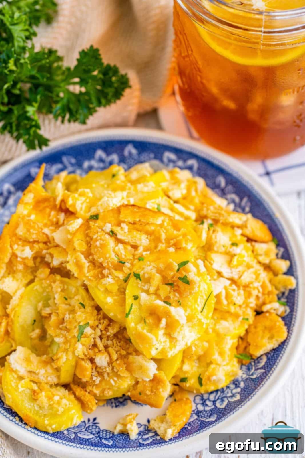 A plate full of fresh made Squash Casserole, garnished with fresh herbs.