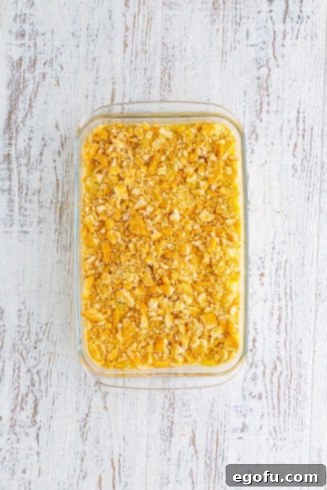 Squash casserole with crushed cracker topping before baking.