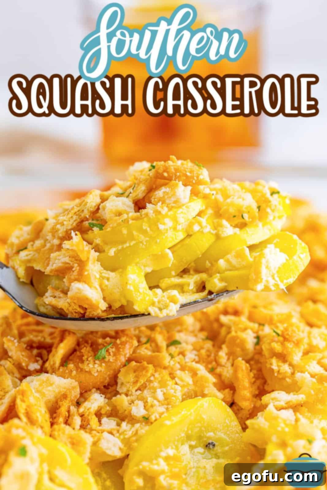 A spoon lifting a creamy bite of squash casserole from a baking dish.