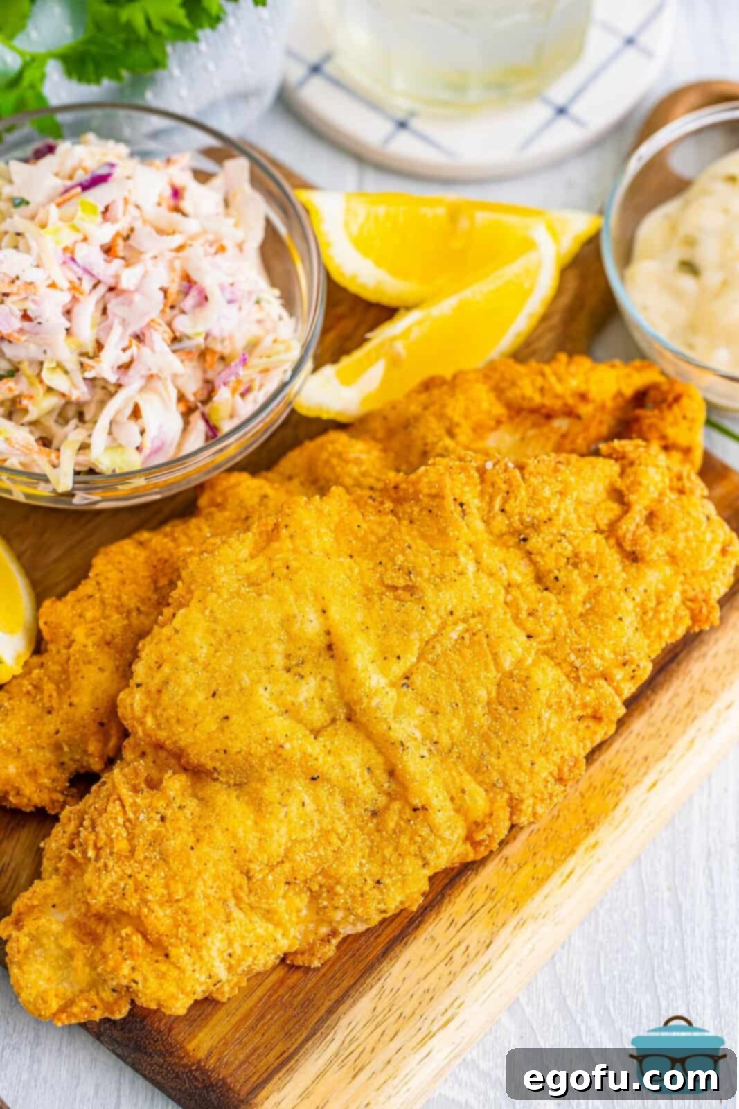 Golden Crispy Catfish 2 Fried Catfish on a wooden serving platter, garnished with lemon wedges and parsley.