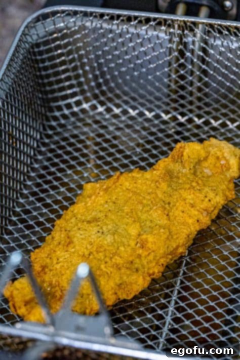 Golden Crispy Catfish 19 A fried catfish fillet in a fryer basket.