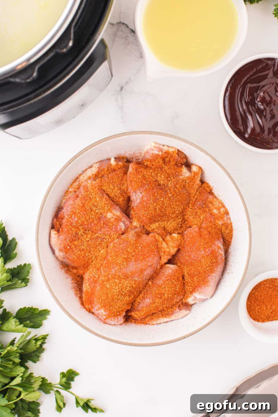 Chicken thighs covered in chicken seasoning in a bowl.