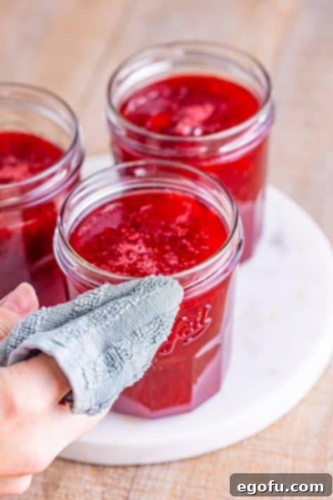From Garden or Freezer: Homemade Strawberry Jam 17 Wiping jars with a cloth.