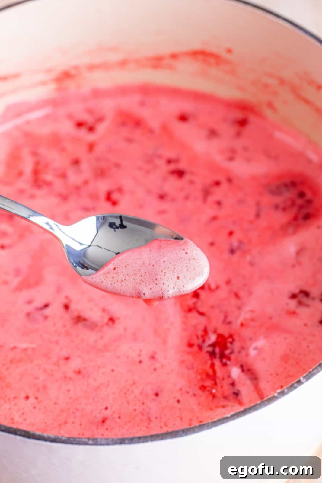 From Garden or Freezer: Homemade Strawberry Jam 5 A spoon skimming off the pink foam.