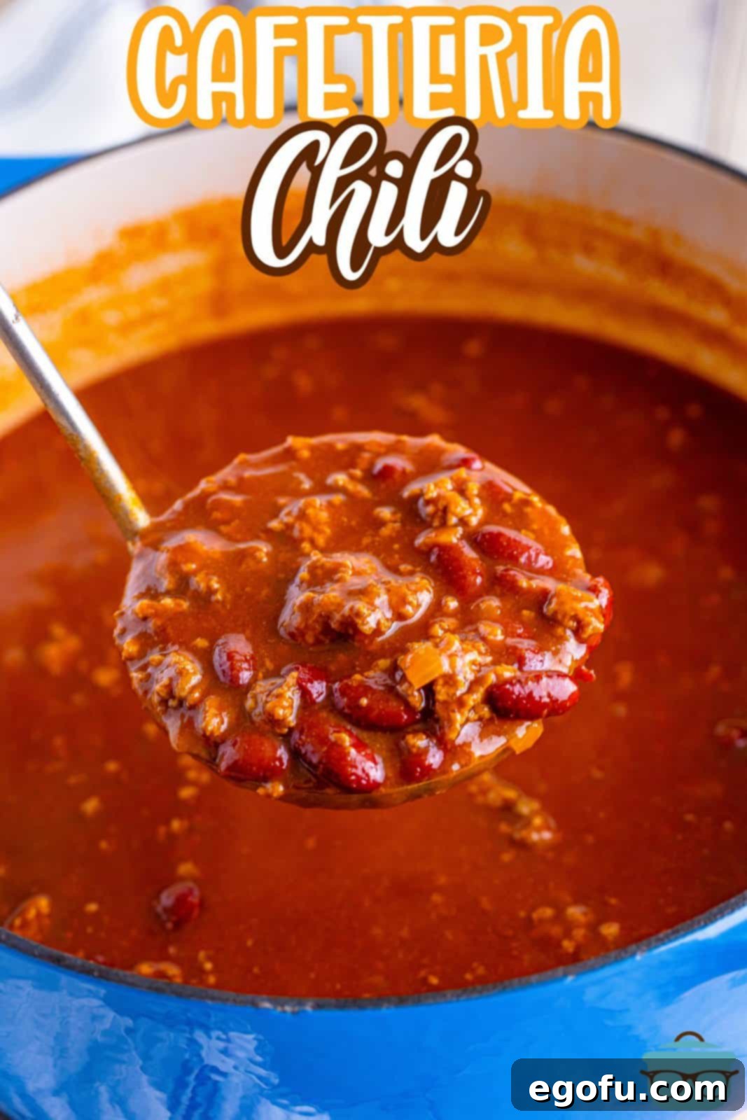 A large pot of Cafeteria Chili simmering to perfection on the stovetop, with a serving utensil holding a portion above the pot.