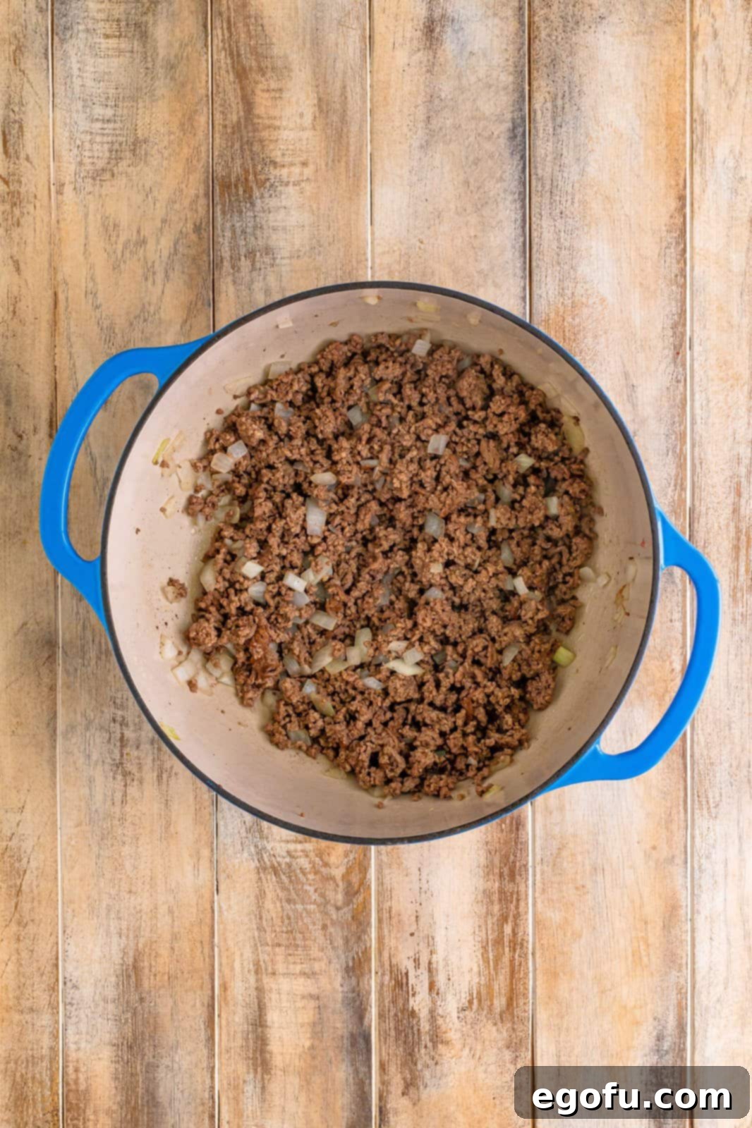 Ground beef and chopped onion cooking in a Dutch oven until browned and fragrant.