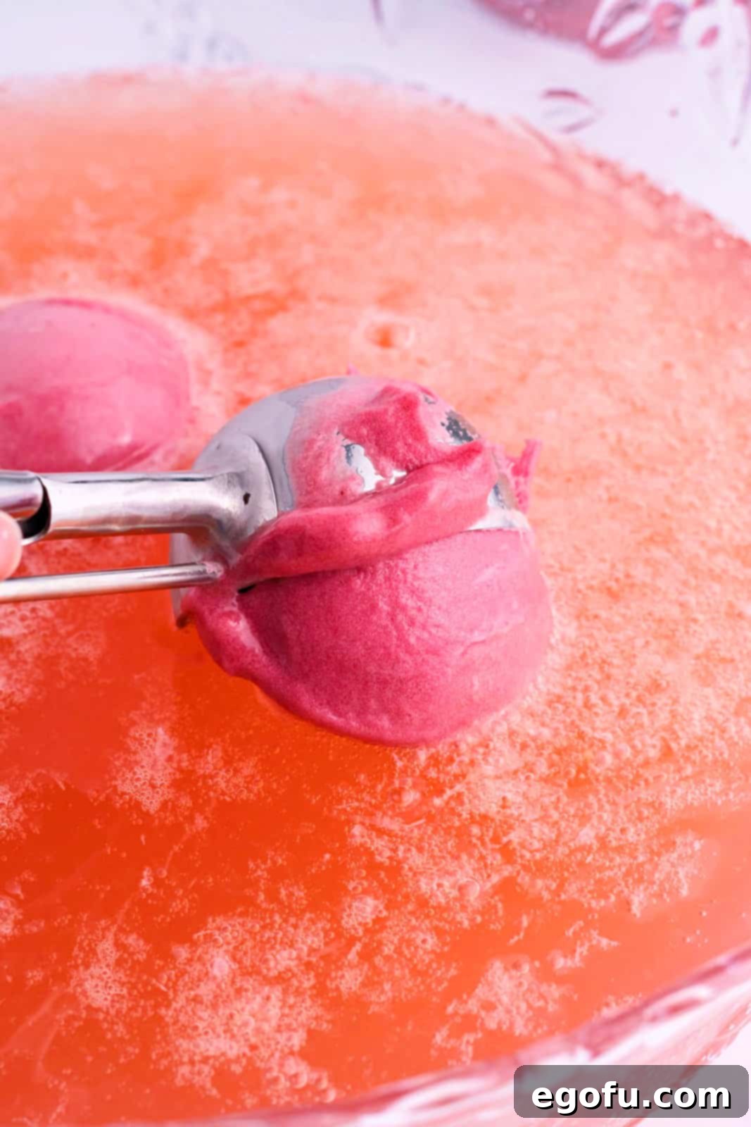 Stork's Sipper 7 Scoops of raspberry sorbet being added to the pink baby shower punch in a punch bowl.