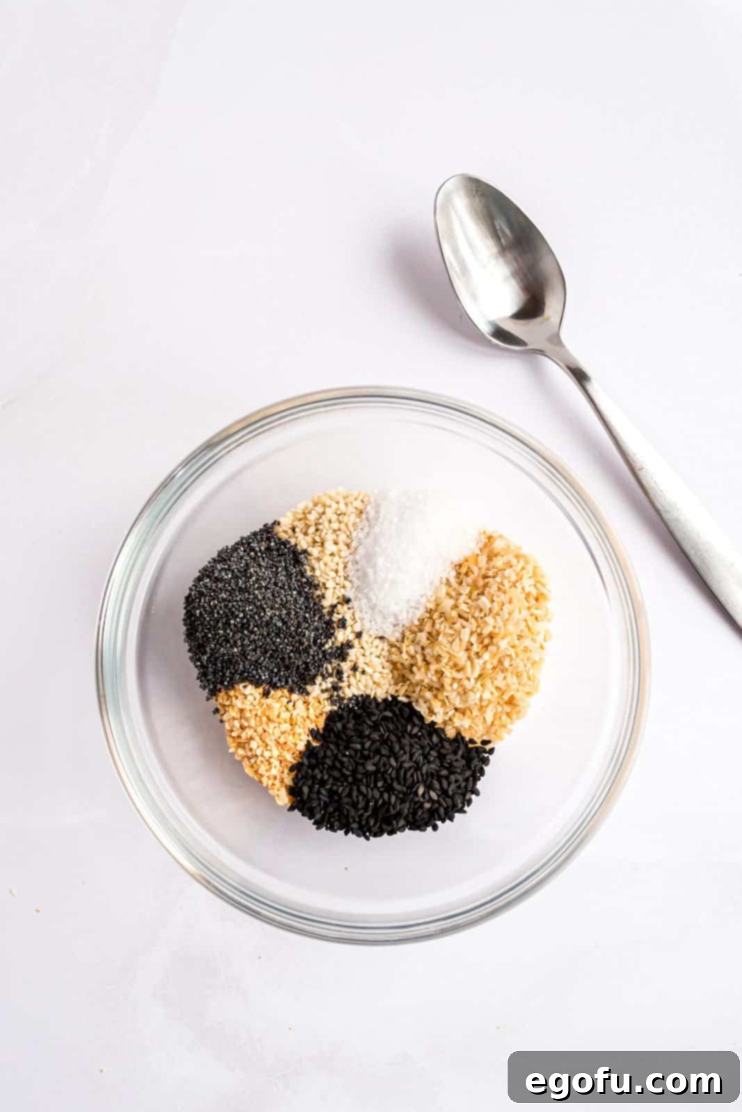 Poppy seeds, white sesame seeds, black sesame seeds, dried minced onion, dried minced garlic, and salt in a mixing bowl.