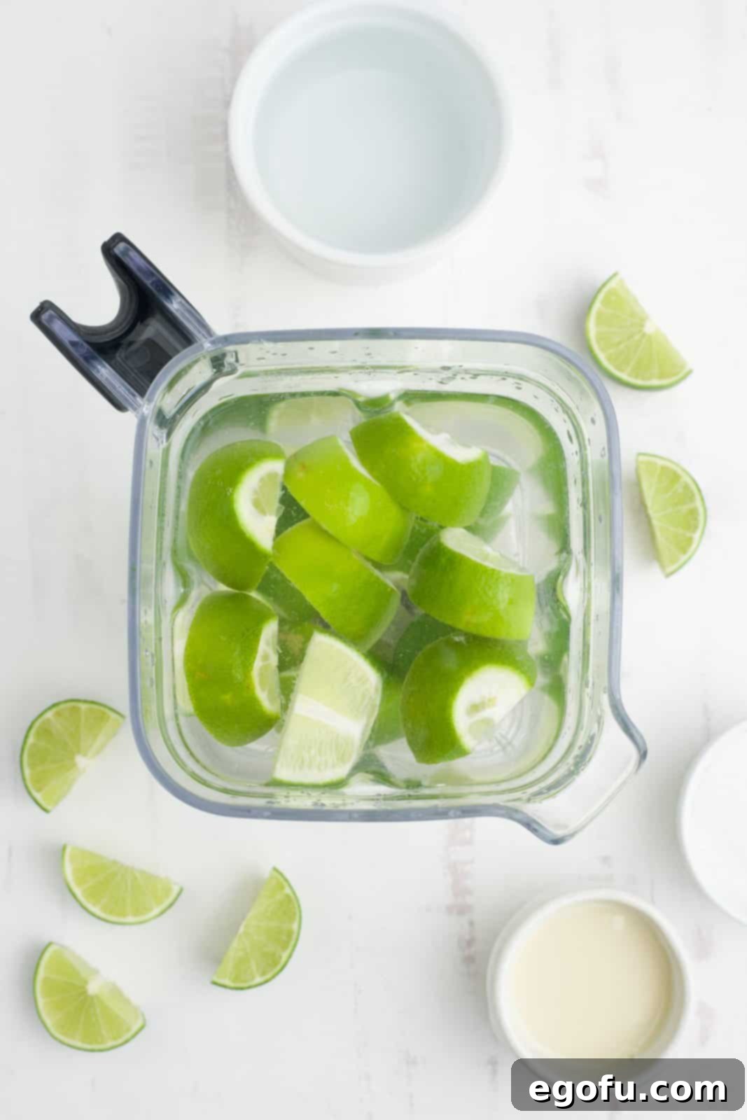 Brazilian Lemon Dream 5 A blender filled with lime wedges, sugar, and water, ready for blending.