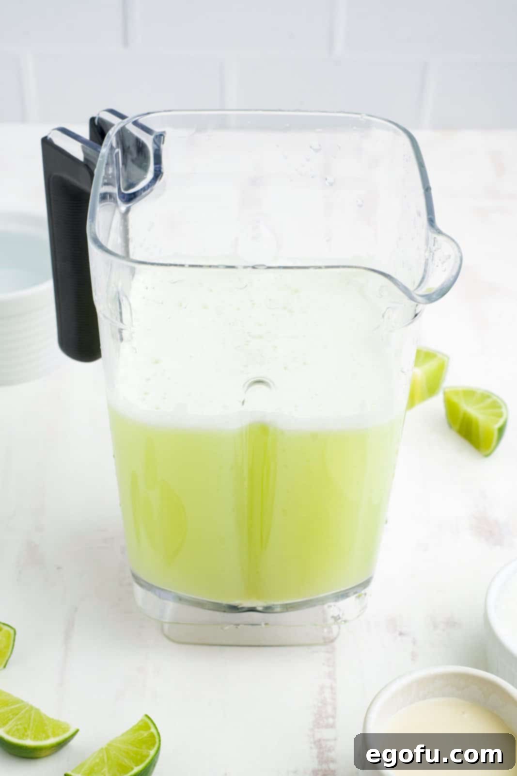 Brazilian Lemon Dream 6 A blender containing the frothy, chunky mixture of blended limes, sugar, and water.