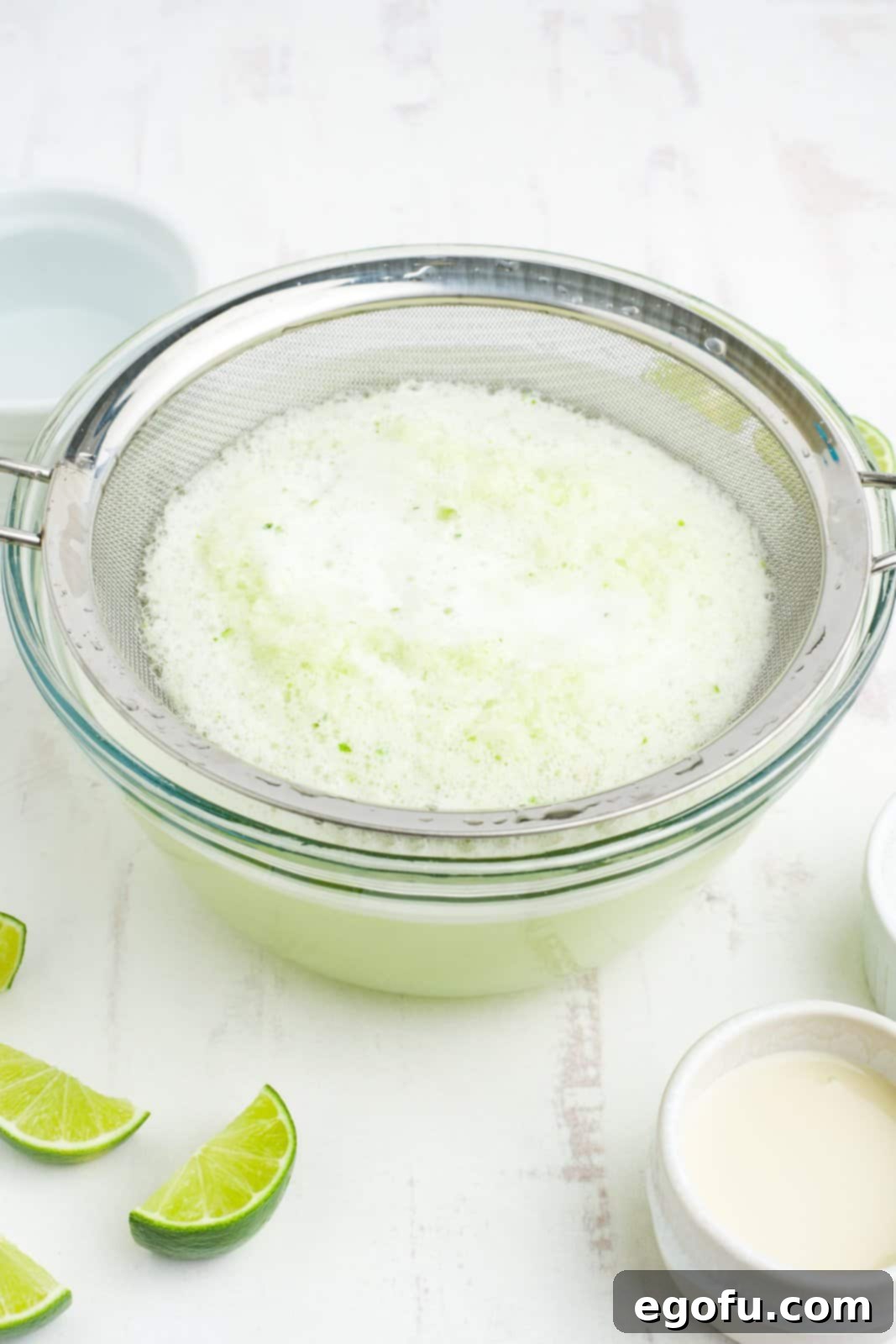 Brazilian Lemon Dream 7 A large bowl with a fine-mesh strainer, capturing lime pulp while the juice drains below.