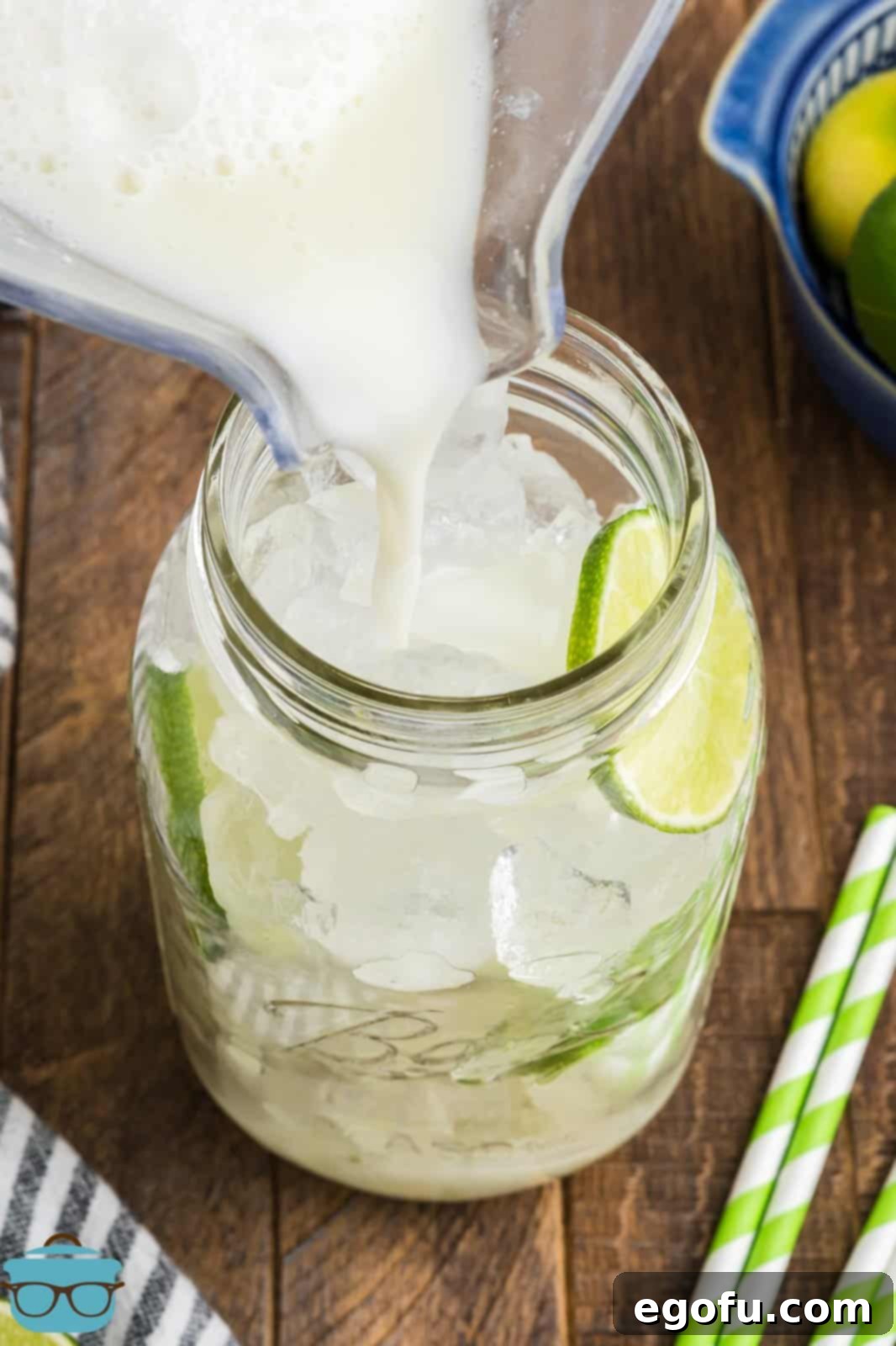 Brazilian Lemon Dream 9 A pitcher pouring Brazilian Lemonade into a glass jar filled with ice.
