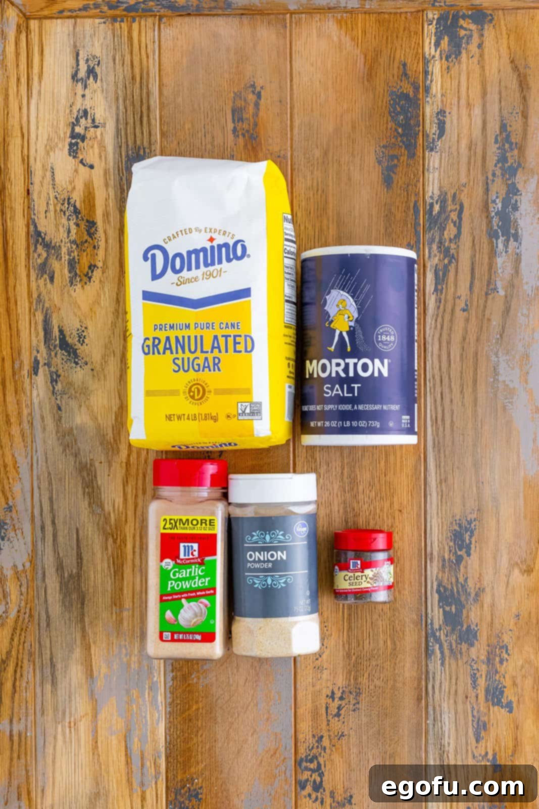 Individual ingredients for Beau Monde Seasoning: celery seed, onion powder, salt, garlic powder, and granulated sugar, laid out.
