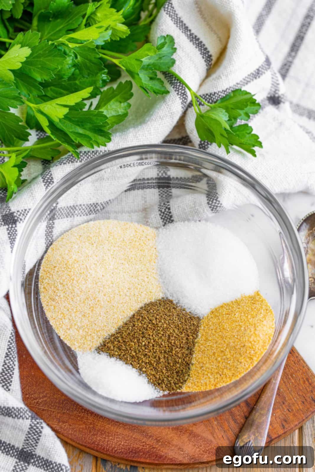 A mixing bowl with celery seed, onion powder, salt, garlic powder, and sugar, before mixing.