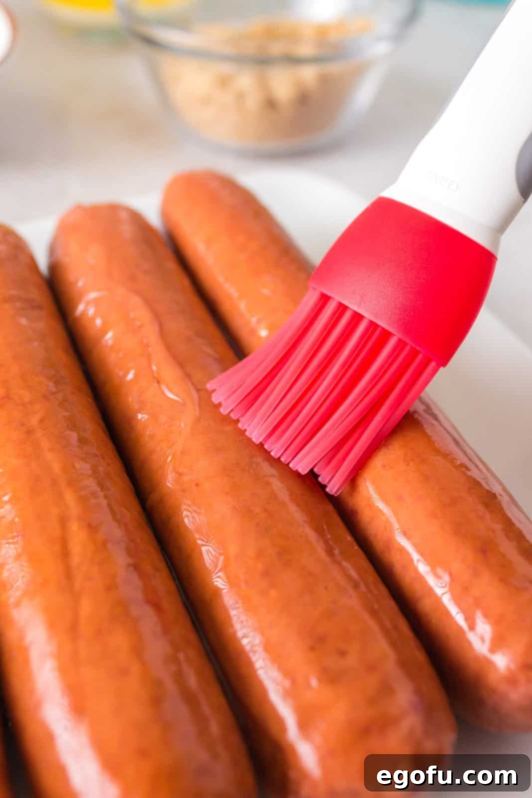 Hot dogs being brushed with olive oil.